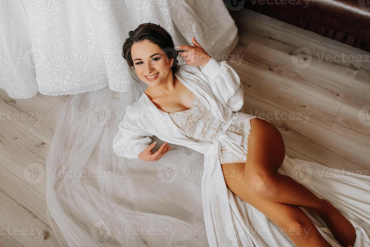 le la mariée dans une dentelle le maillot de corps et soie peignoir mensonges sur le sol et pose dans sa chambre. ouvert jambes. Matin de le la mariée photo