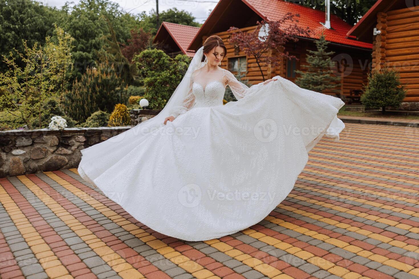 une roux la mariée est encerclant dans sa mariage robe, contre le Contexte de montagnes et en bois Maisons. magnifique robe avec longue manches, ouvert bousiller. photo