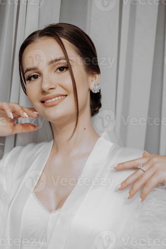 portrait de la mariée fille dans blanc robe avec professionnel coiffure et Naturel maquillage dans Hôtel pièce avec réflexion dans la fenêtre. le meilleur journée photo