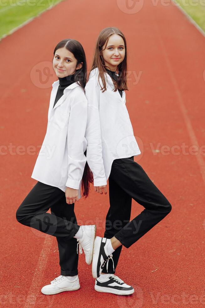 portrait de deux adolescent les filles dans décontractée vêtements séance dans une stade et posant à la recherche à le caméra. concept de amitié. une moment de Bonheur. photo