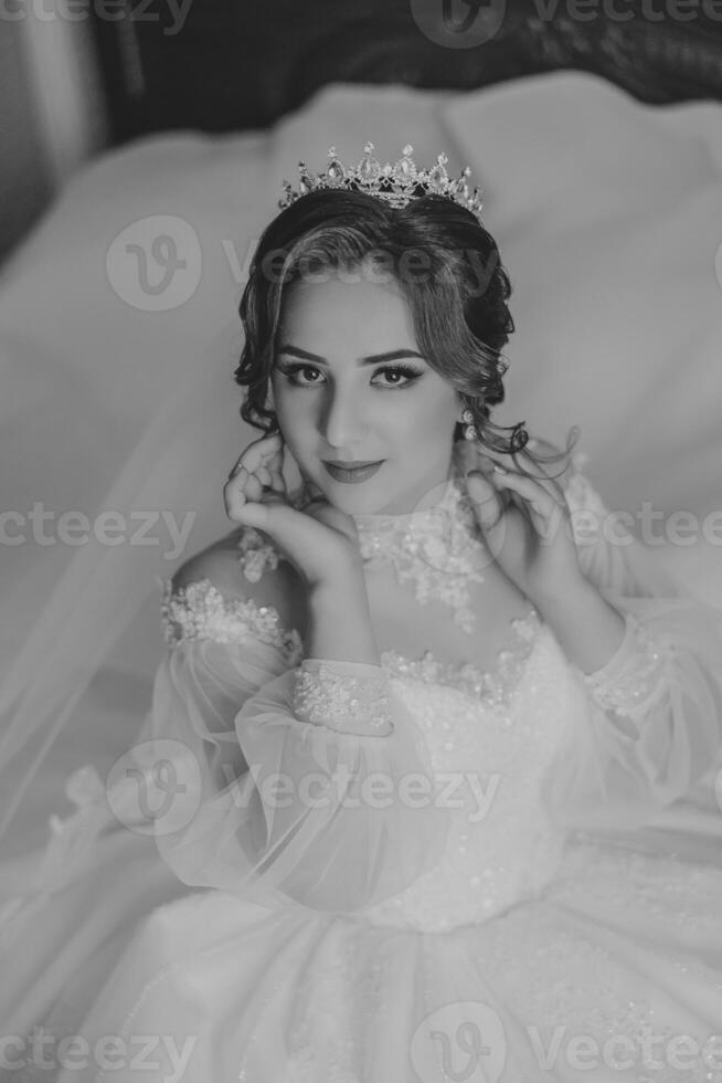 mode photo de une magnifique la mariée avec foncé cheveux dans un élégant mariage robe et étourdissant maquillage dans le pièce sur le Matin de le mariage. le la mariée est en train de préparer pour le mariage