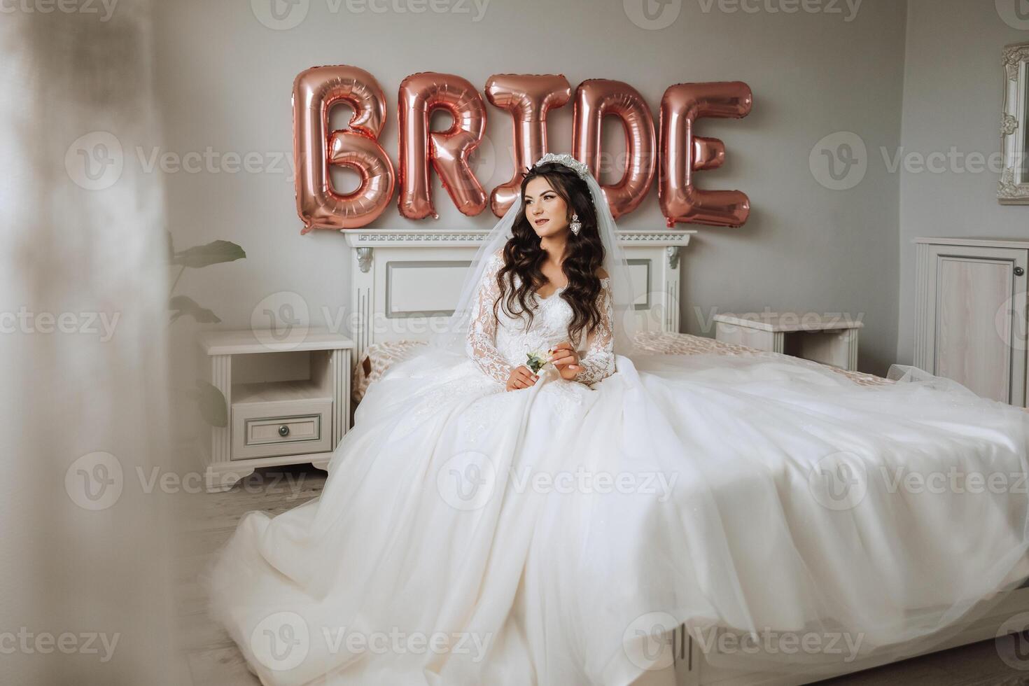 une magnifique magnifique portrait de une Jeune la mariée. magnifique la mariée avec mariage maquillage et bijoux couronne sur longue frisé cheveux. mariage photo modèle avec marron yeux dans une magnifique intérieur.