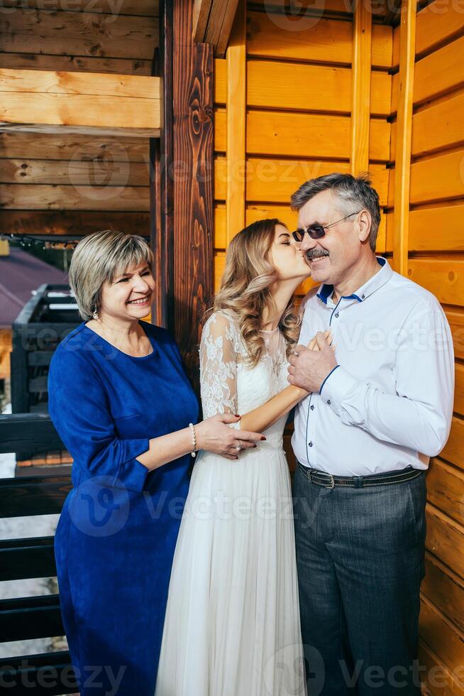 content Parents réjouir pour leur fille, qui volonté bientôt avoir marié. émouvant des moments à le mariage. maman et papa étreinte fille la mariée. portrait de Parents avec la mariée photo