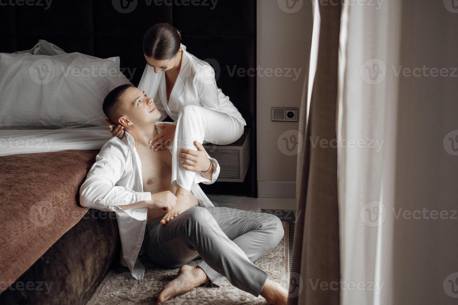 sensuel et soumissionner Matin de le la mariée et jeune marié dans le Hôtel chambre. content et dans l'amour les mariées et les palefreniers. sur de soi fille la mariée et Beau jeune marié. préparation pour le mariage photo