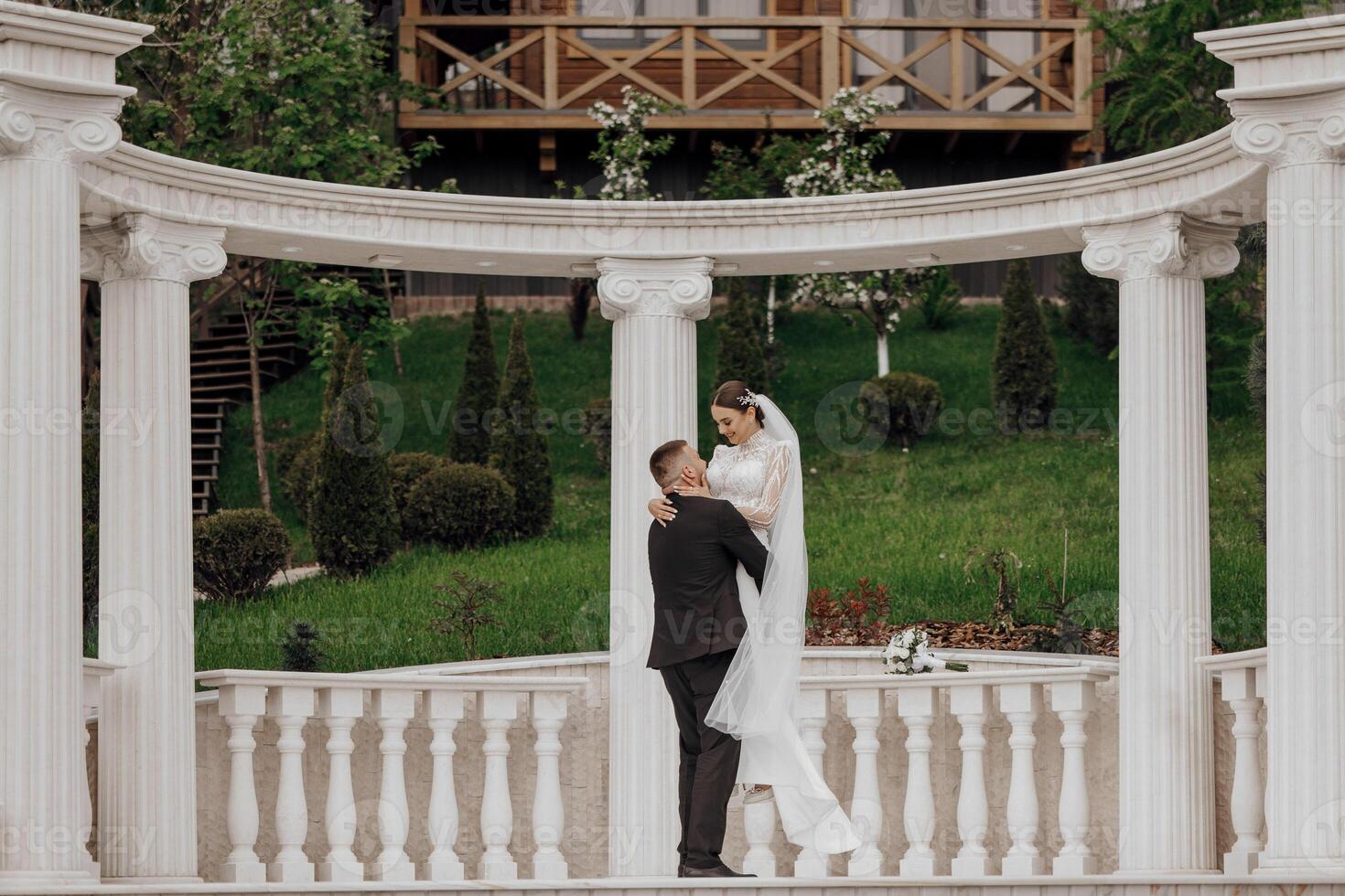 le la mariée et jeune marié embrasse près le de style romain Colonnes. un exquis mariage photo