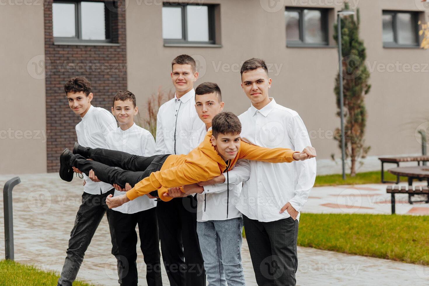 groupe de souriant et content adolescent copains portant décontractée vêtements dépenses temps ensemble, posant et parlant avec chaque autre près Université bâtiment sur l'automne journée. photo