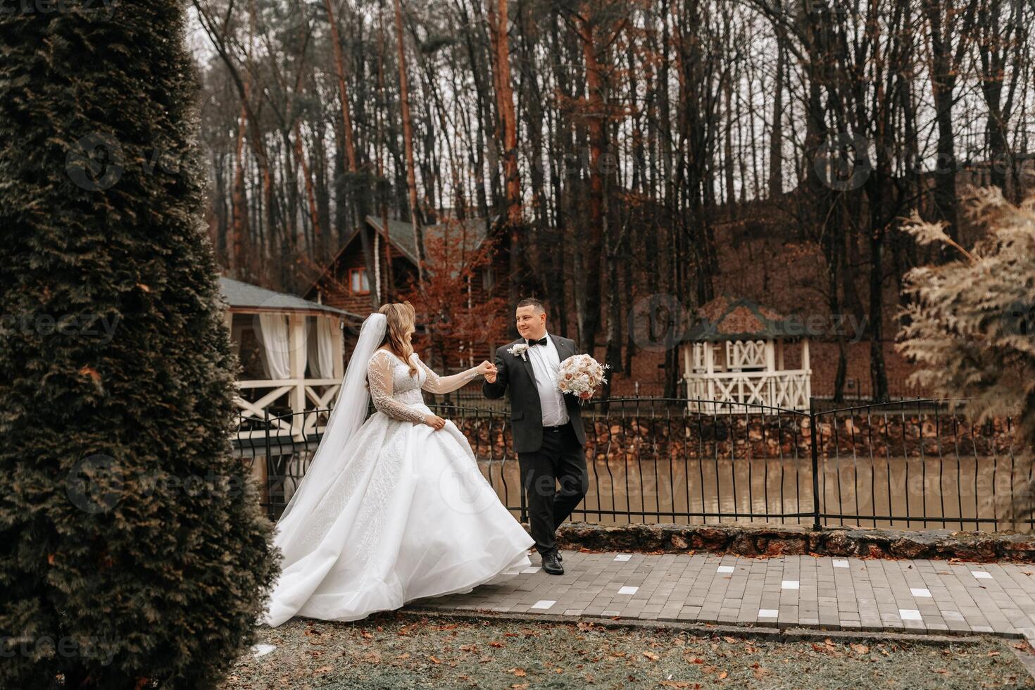 le la mariée et jeune marié sont en marchant près le Hôtel et poser, content et profiter le jour, en portant mains. une longue train sur le robe. hiver mariage photo