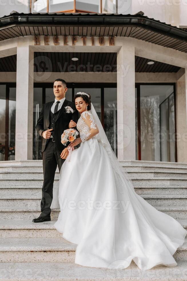 mariage couple dans l'amour. une magnifique la mariée et un élégant jeune marié tendrement embrasse et prendre plaisir le journée. une élégant couple de jeunes mariés. concept de mariage photo