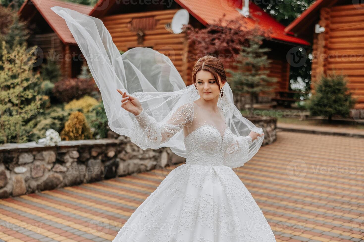 une roux la mariée virevolte sa longue voile contre une Contexte de en bois Maisons. magnifique robe avec longue manches, ouvert bousiller. été mariage photo