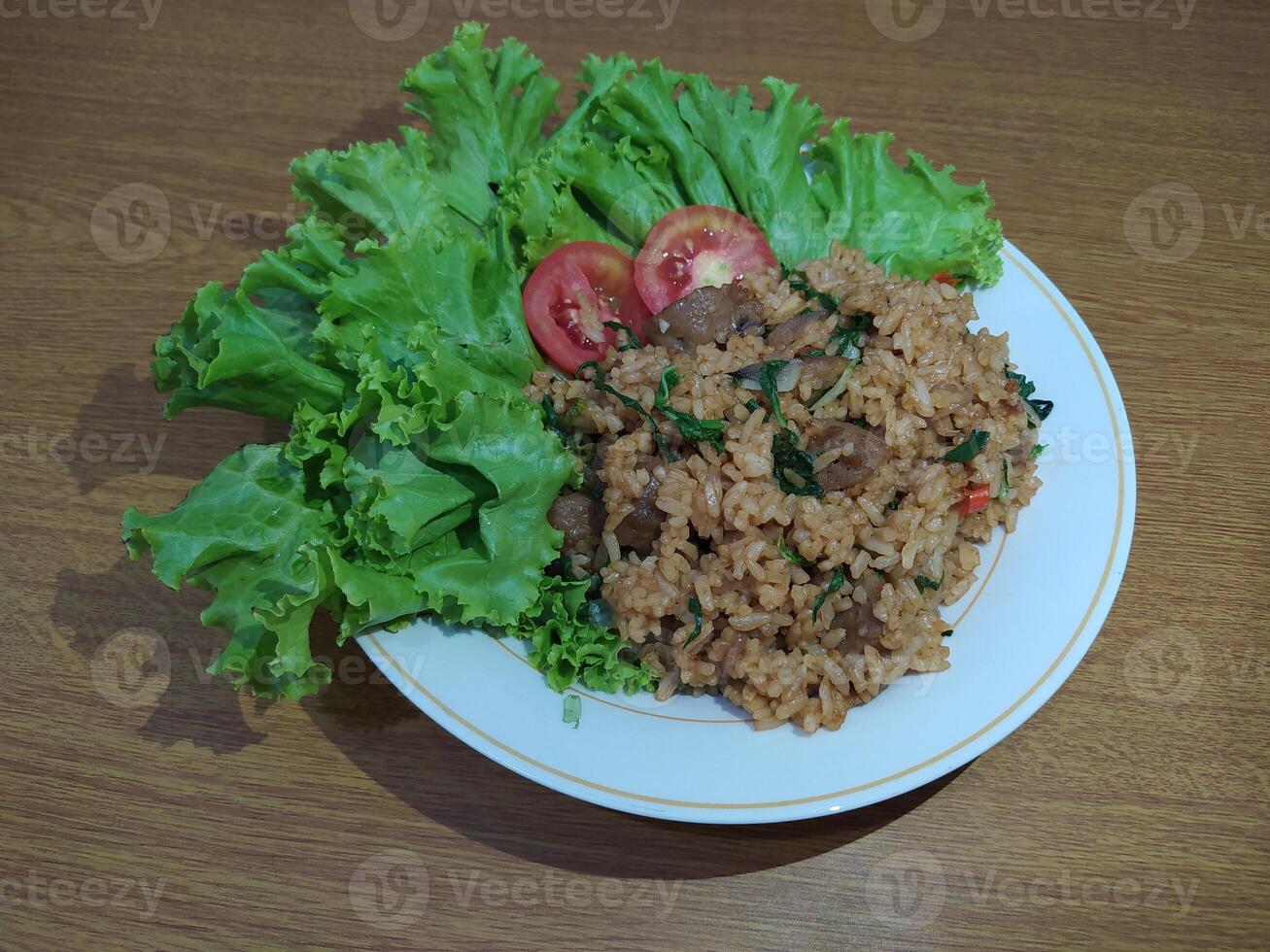 délicieux indonésien frit riz nasi goreng avec beaucoup de laitue, moutarde légumes verts et tomates servi sur une blanc assiette photo