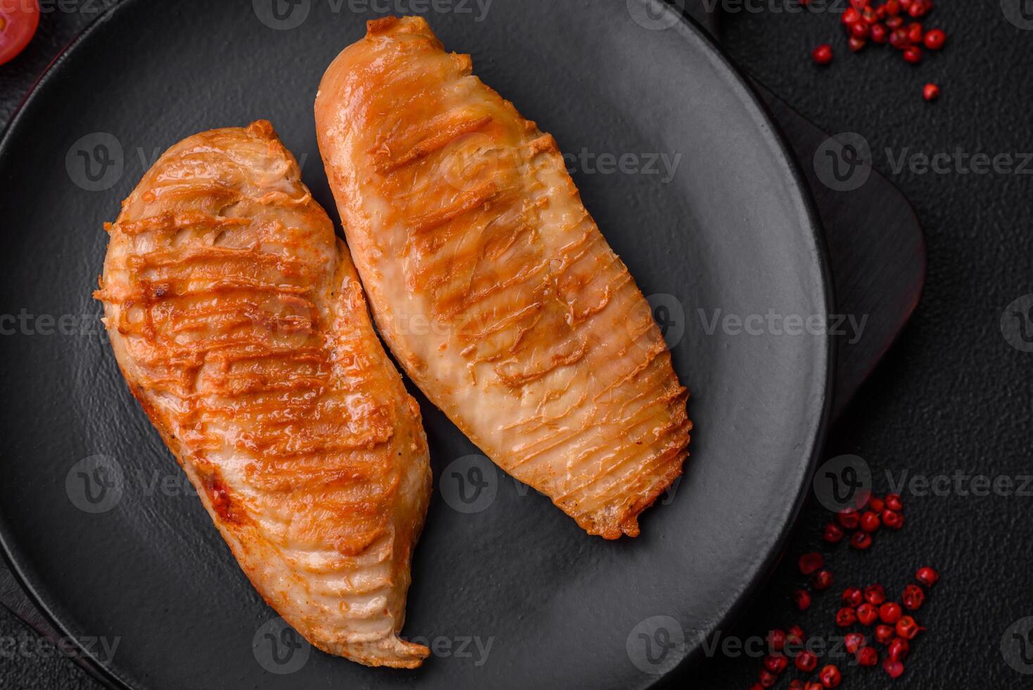 délicieux filet de poulet grillé frais avec des épices et des herbes sur un fond de béton foncé photo