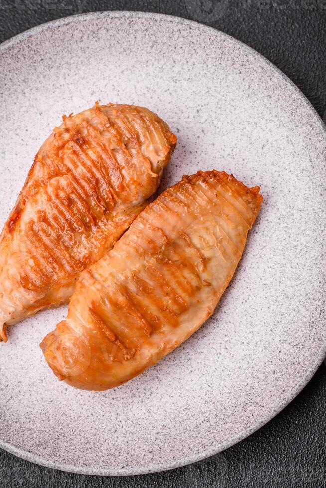 délicieux filet de poulet grillé frais avec des épices et des herbes sur un fond de béton foncé photo