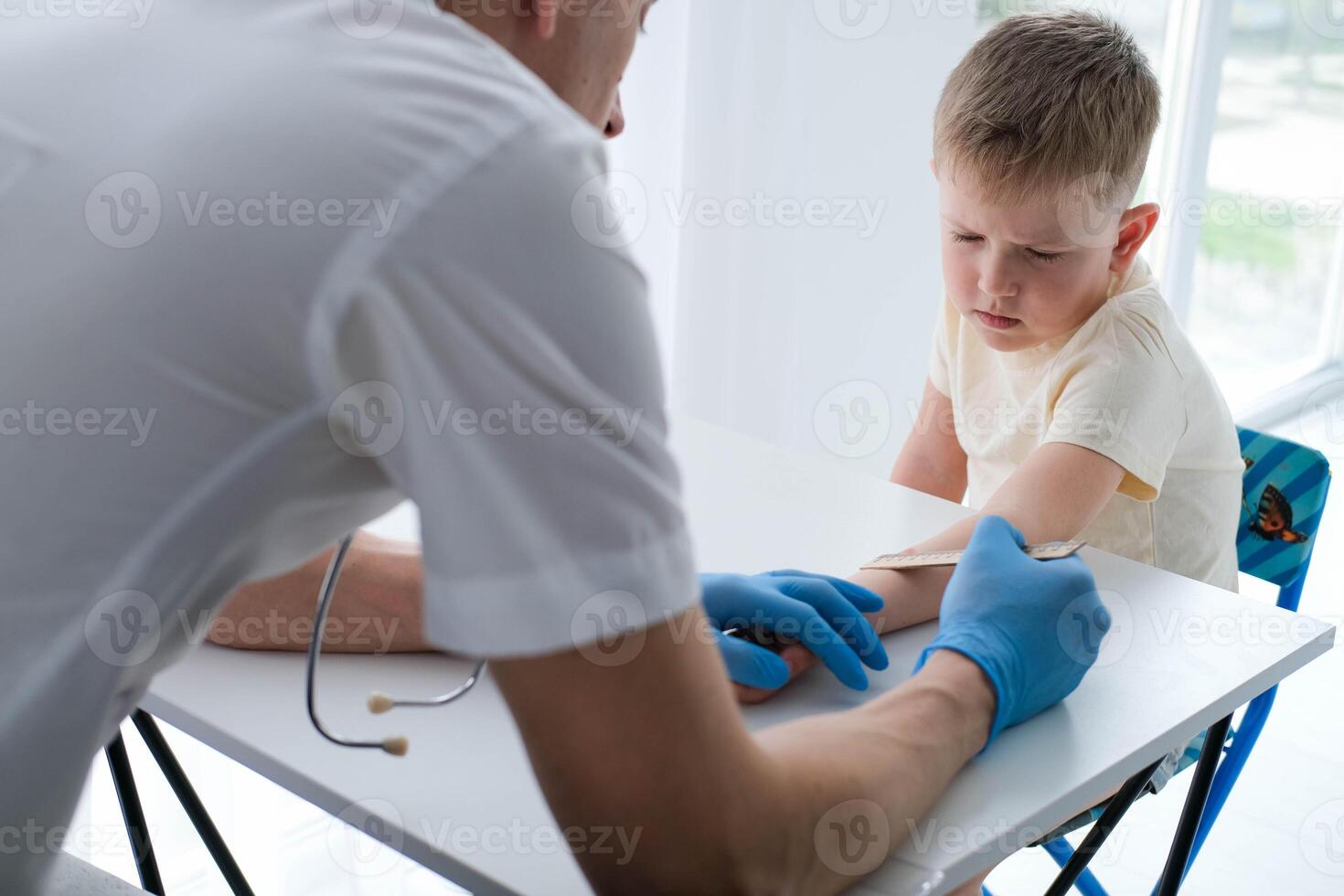 une Masculin médecin fait du un important mantoux tester sur une enfant. le médecin les mesures le mantoux tester avec une règle pour une peu garçon photo