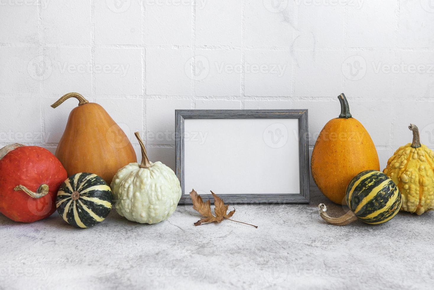 cadre photo et décor de citrouille sur la table sur fond de carreaux blancs.