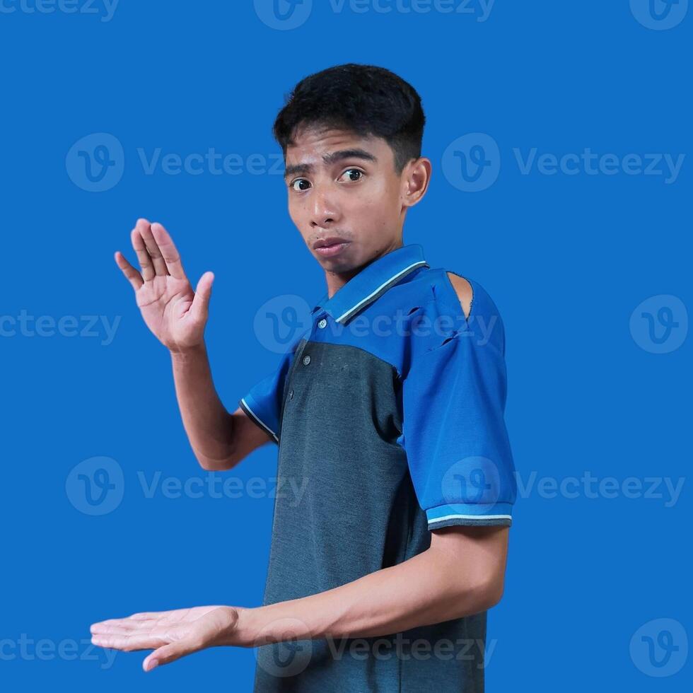 surpris asiatique homme avec tous les deux mains formant une photocopie dans le milieu, portant une bleu T-shirt. Contexte isolé bleu Couleur photo