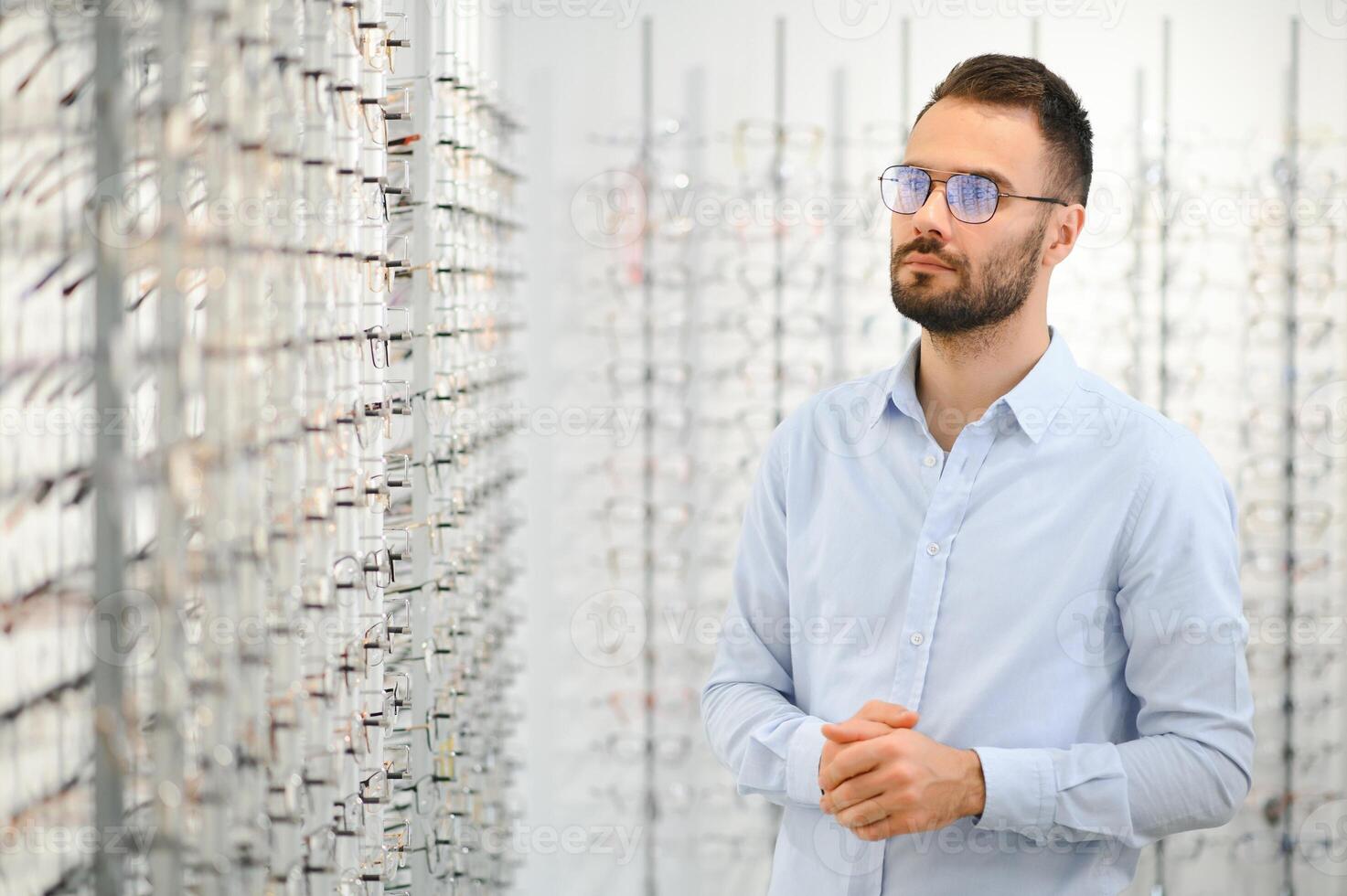 Jeune homme choisir lunettes à optique magasin photo