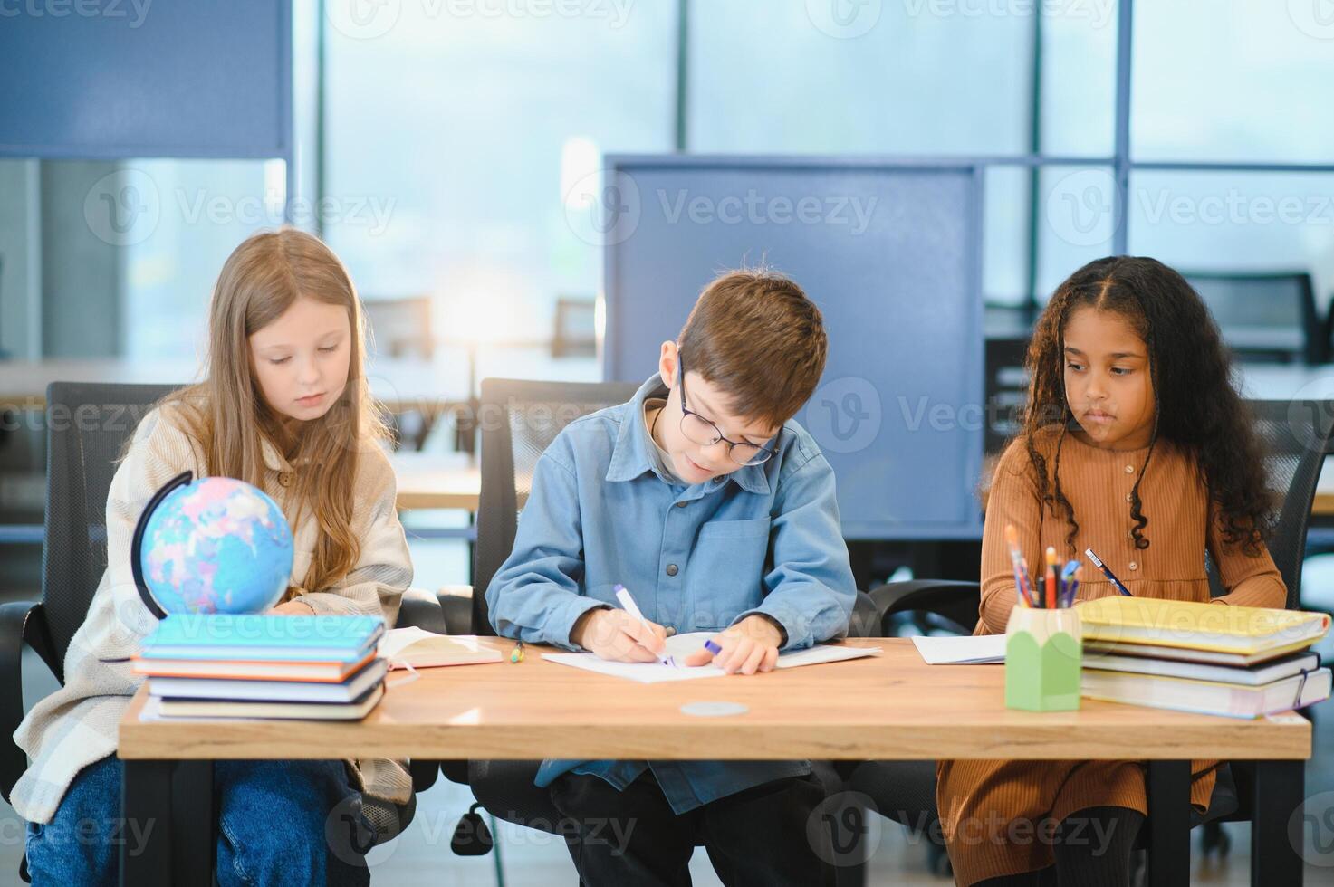 concentré multiracial élèves des gamins l'écriture vers le bas Les données dans carnet tandis que séance à table photo