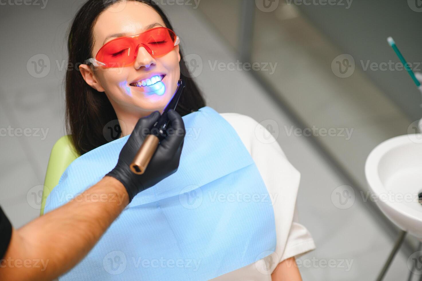 Jeune femme avoir dentaire remplissage séchage procédure avec guérir uv lumière à dentaire clinique photo