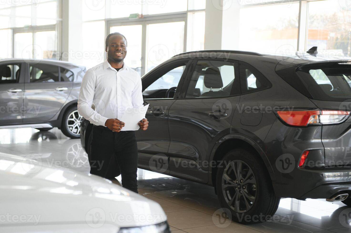 voitures concession concept. auto vendeur afro homme permanent dans voiture centre photo