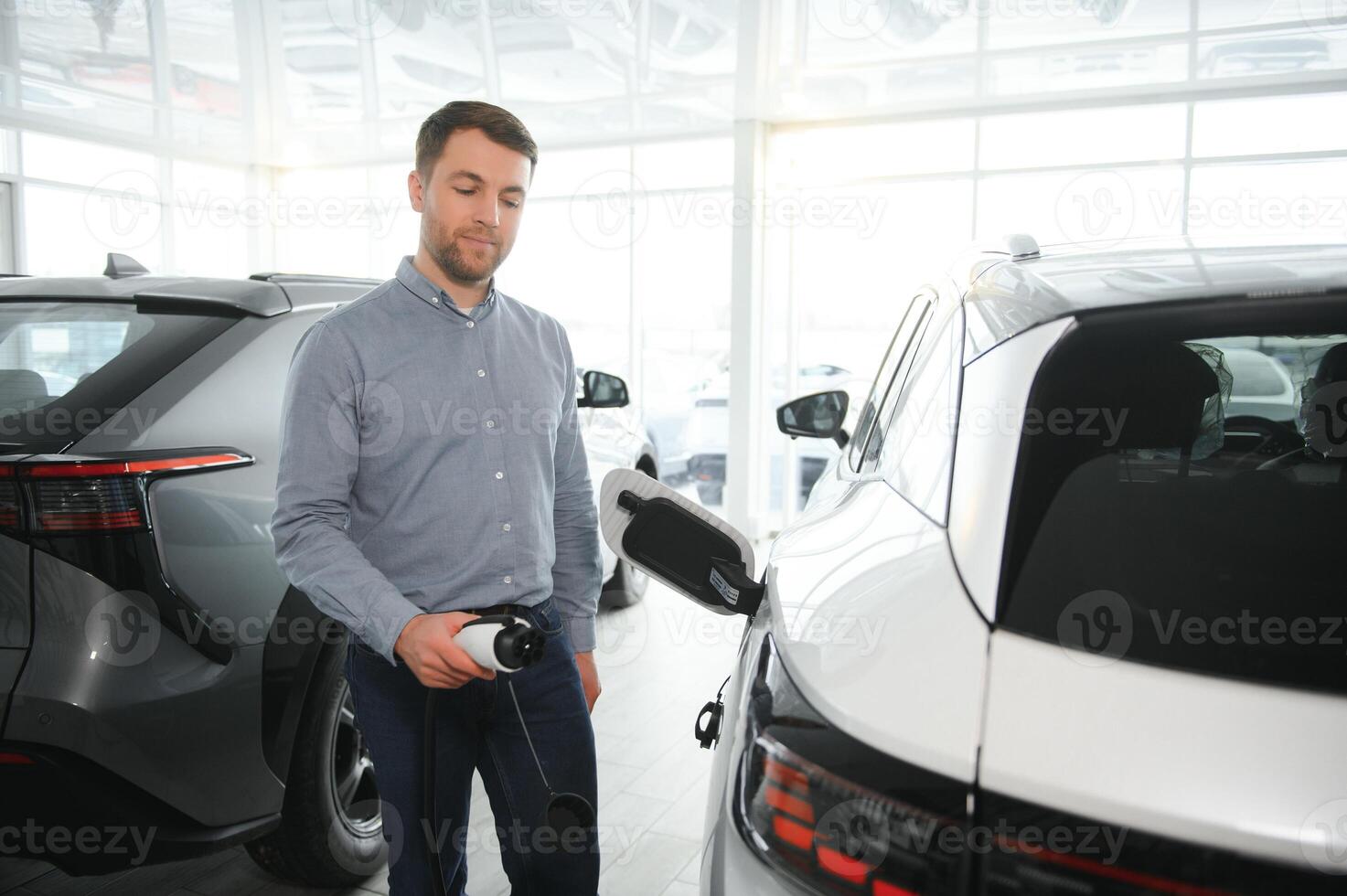 barbe homme en essayant une Nouveau mise en charge câble avec une voiture mise en charge station à le moteur concession. concept de achat électrique véhicule. intelligent écologique vivant photo