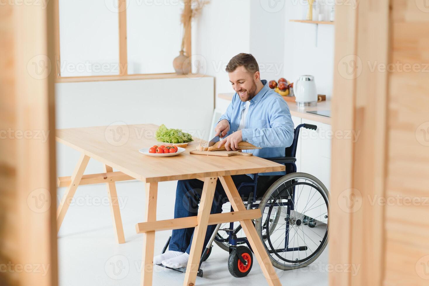 Jeune désactivée homme séance sur roue chaise en train de préparer nourriture dans cuisine photo