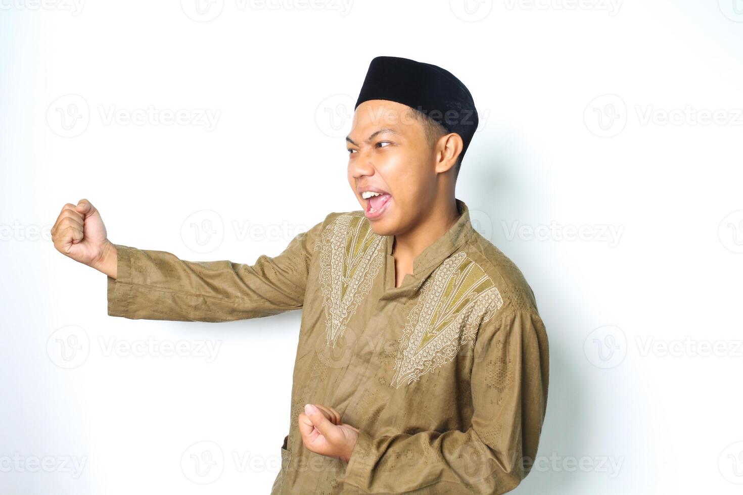 excité asiatique musulman homme portant islamique vêtements élevage poing montrant la victoire geste dans eid mubarak fête isolé sur blanc geste photo