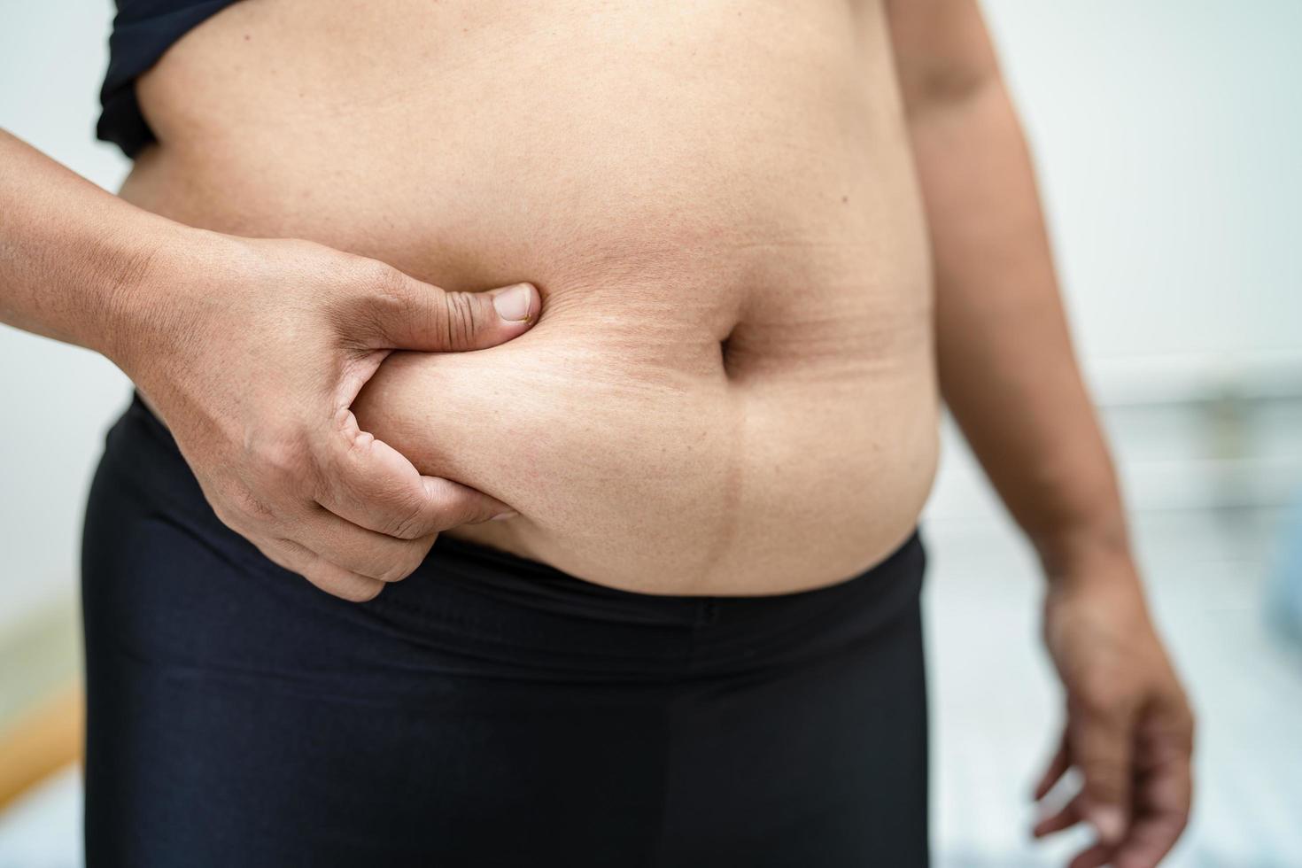 une femme asiatique en surpoids montre un gros ventre au bureau. photo