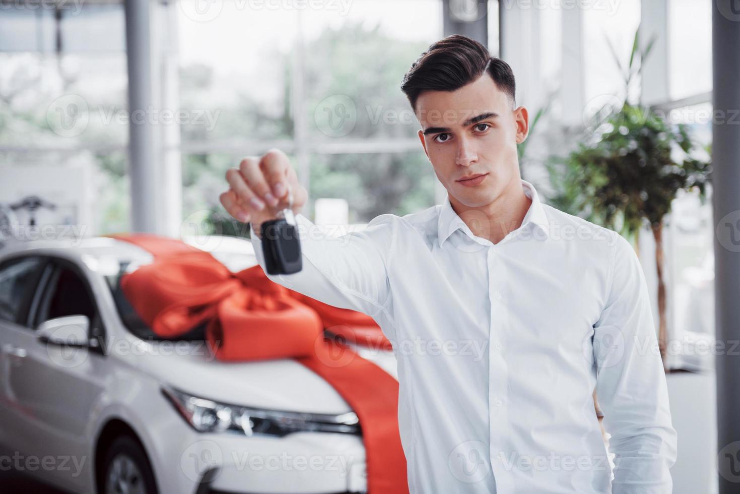 jeune homme heureux avec des clés dans ses mains, chanceux d'acheter une voiture photo