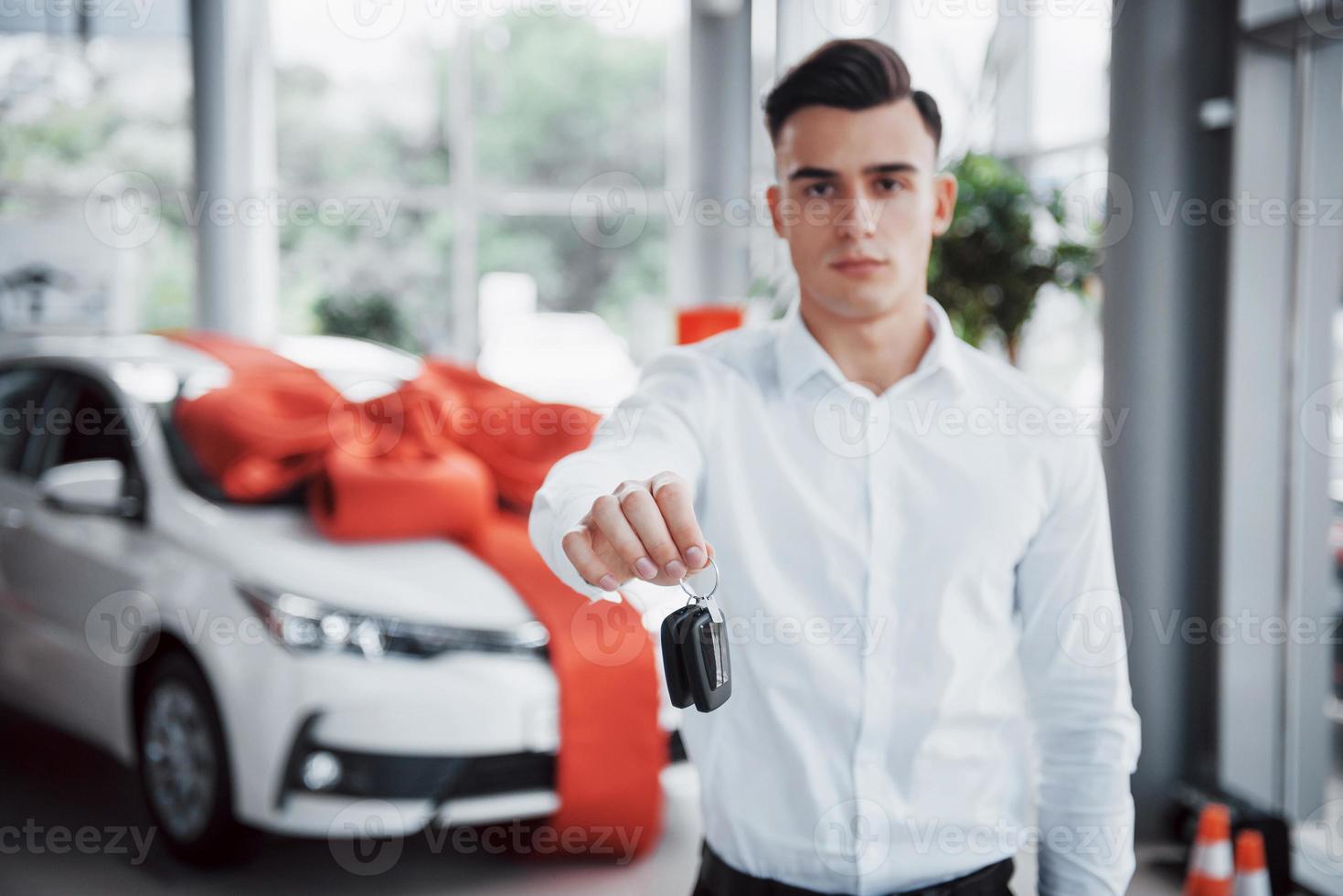 jeune homme heureux avec des clés dans ses mains, chanceux d'acheter une voiture photo