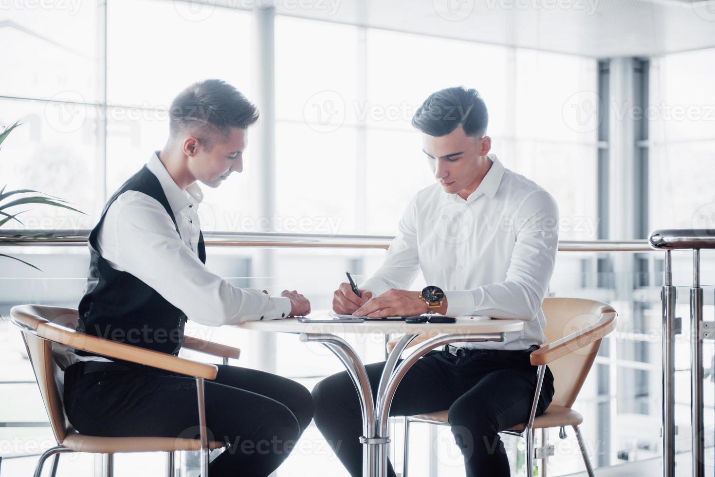 deux hommes d'affaires signent des documents dans un grand bureau spacieux photo