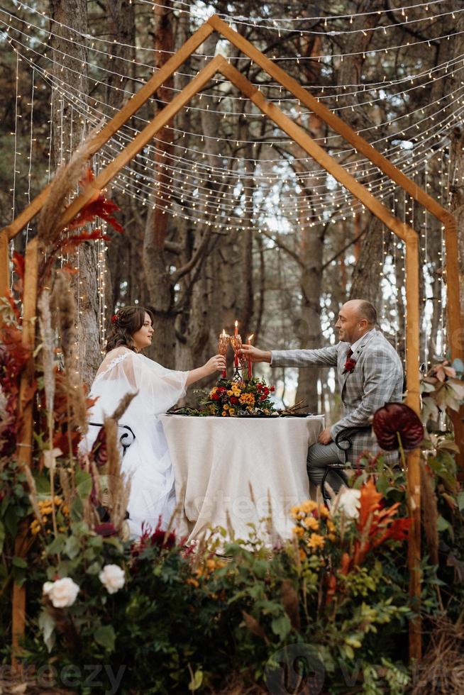 dîner de mariage d'un couple de jeunes mariés dans la forêt d'automne photo
