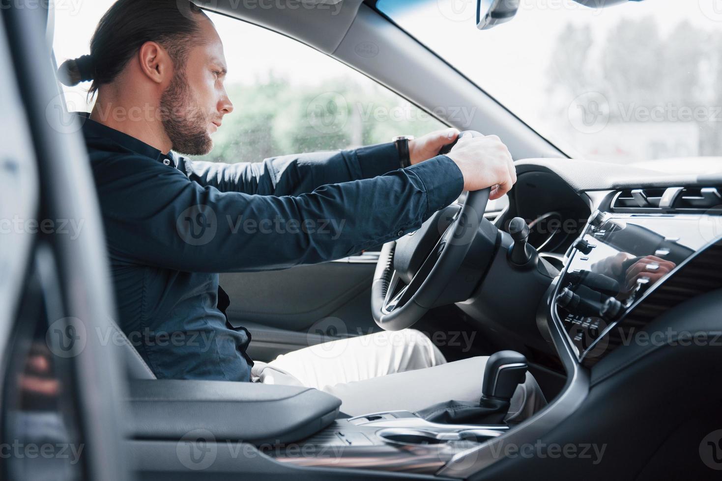 jeune homme d'affaires confiant assis au volant de sa nouvelle voiture photo