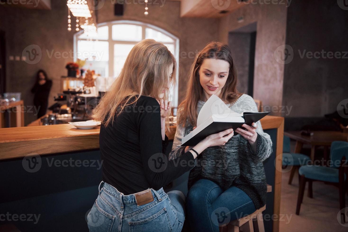 deux jeunes femmes assises dans le café buvant du café et profitant de bons livres. étudiants en pause-café. éducation, concept de mode de vie photo
