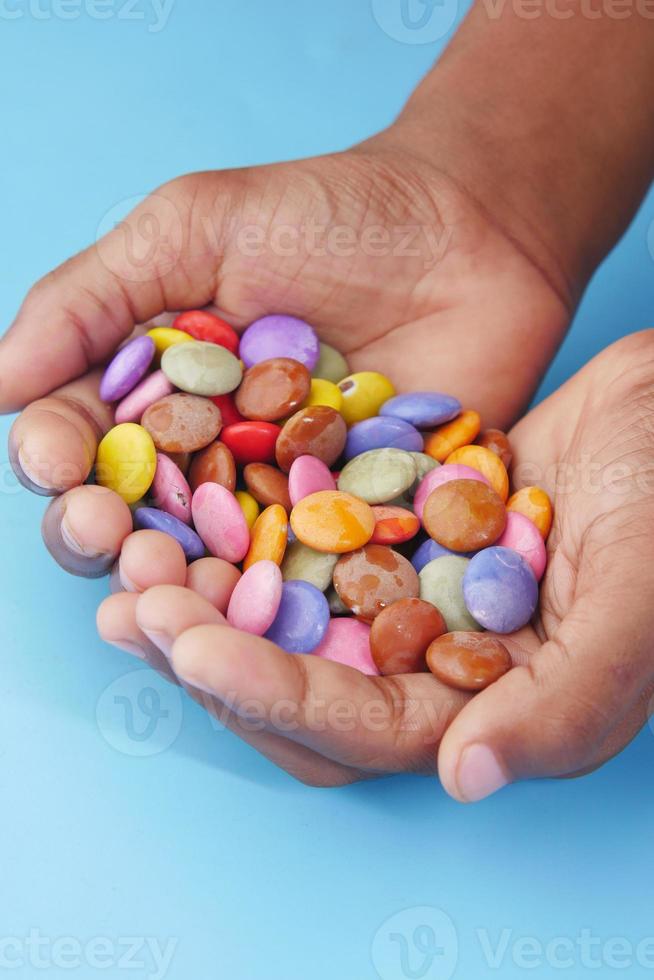Garçon enfant ramasser des bonbons sucrés multicolores dans un bol close up photo