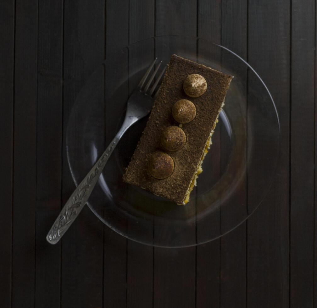 truffe gâteau sur verre assiette sur foncé en bois tableau. photo