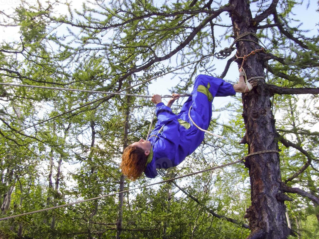 une touristique fille grimpe une corde entre le des arbres photo