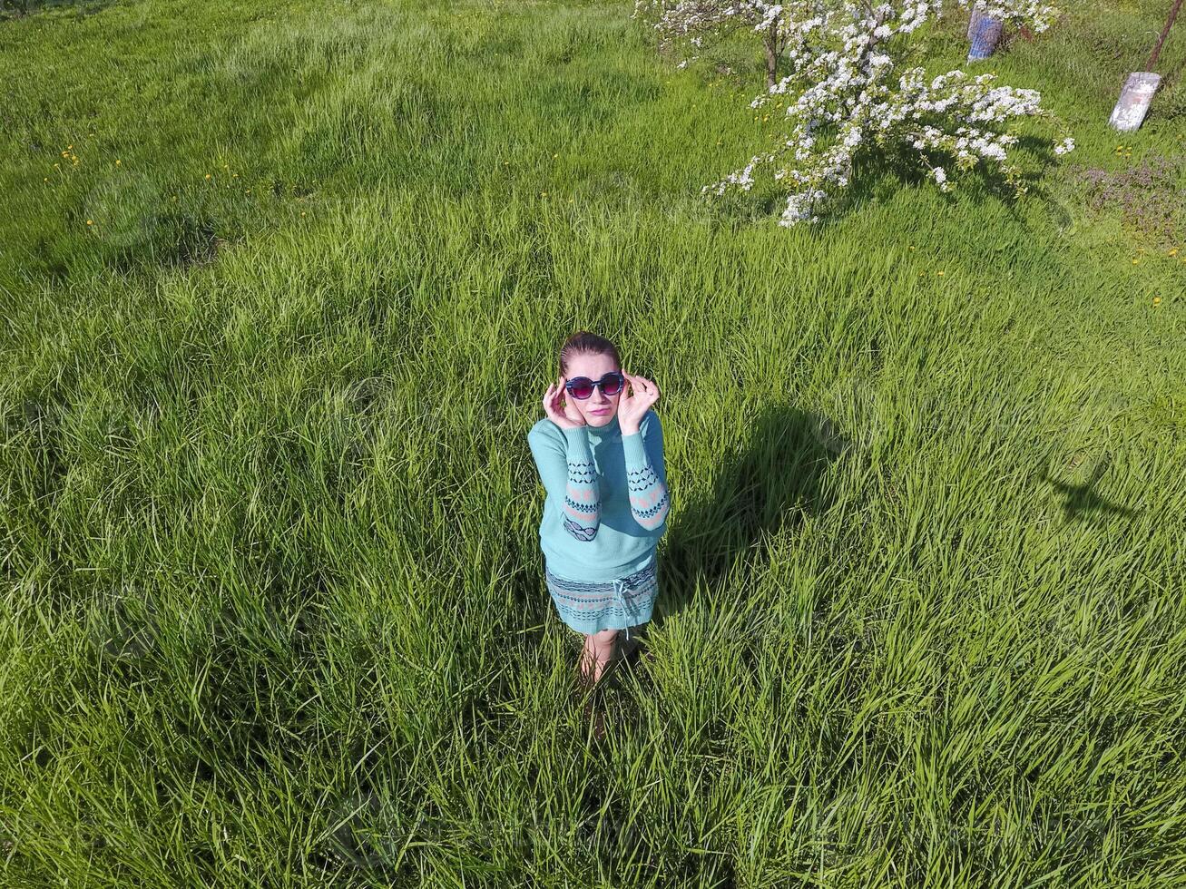 Jeune fille dans une lumière vert robe sur le pelouse avec vert herbe. photo