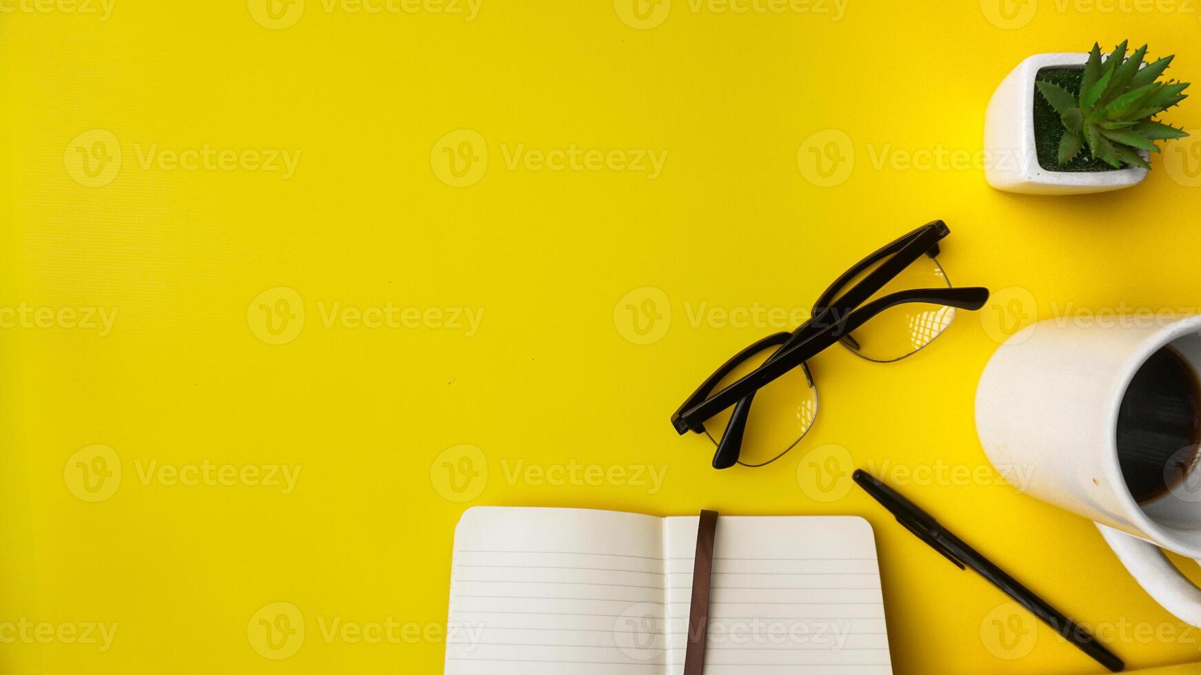 espace de travail bureau avec des cahiers, des stylos, lunettes, végétaux, et café sur bleu Contexte photo