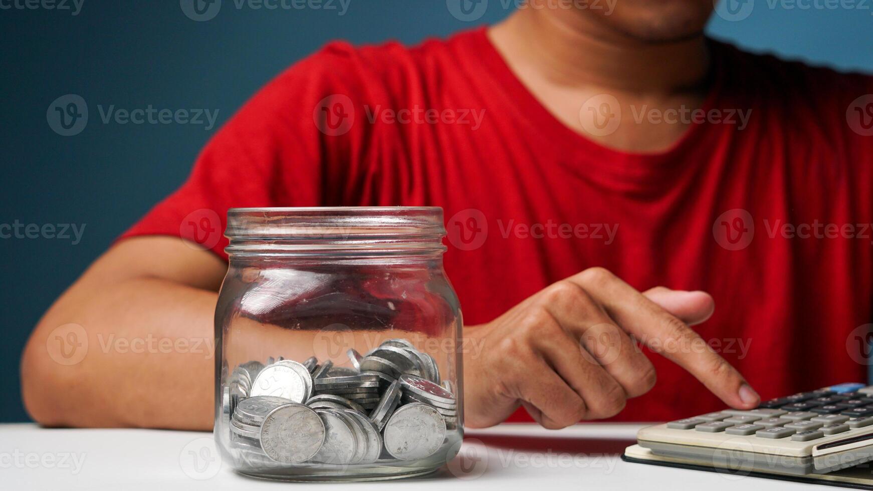 homme avec pièces de monnaie dans une clair transparent verre pot. économie argent concept photo