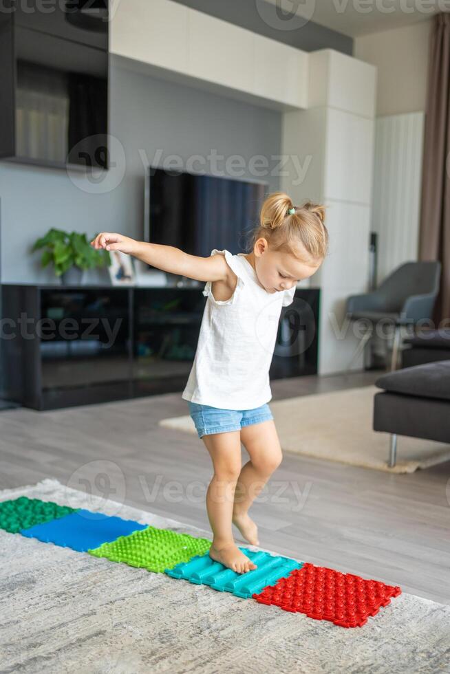 peu fille des promenades sur une massage tapis. bambin bébé pied massage tapis. des exercices pour jambes orthopédique massage tapis. photo