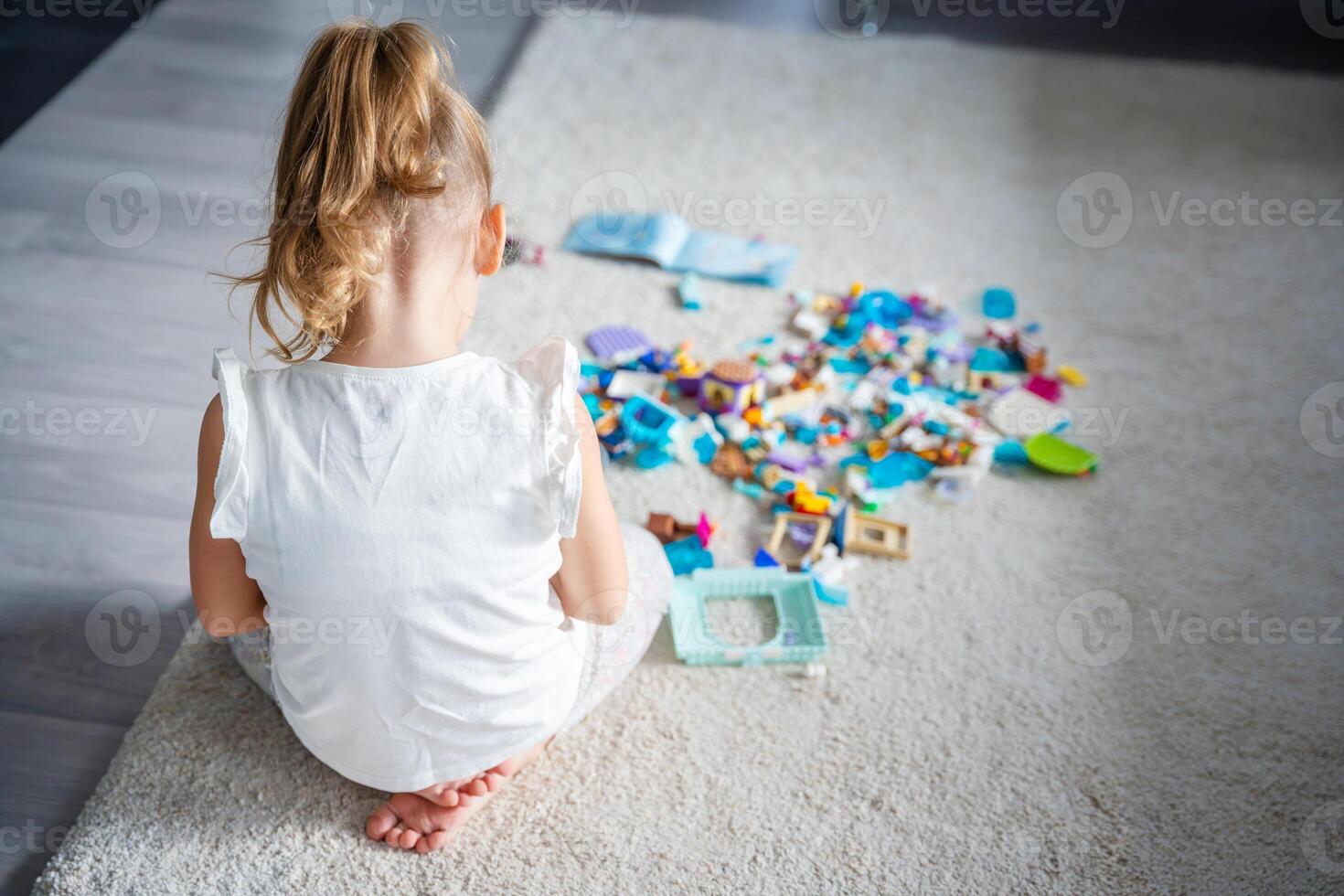 vue de le retour de peu fille en jouant avec petit constructeur jouet sur sol dans maison, éducatif jeu, dépenses loisir Activités temps concept photo