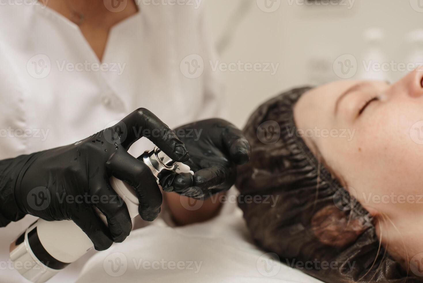fermer de le esthéticienne mains appliquant crème à le du client visage et Faire une massage. faciale peau se soucier. photo