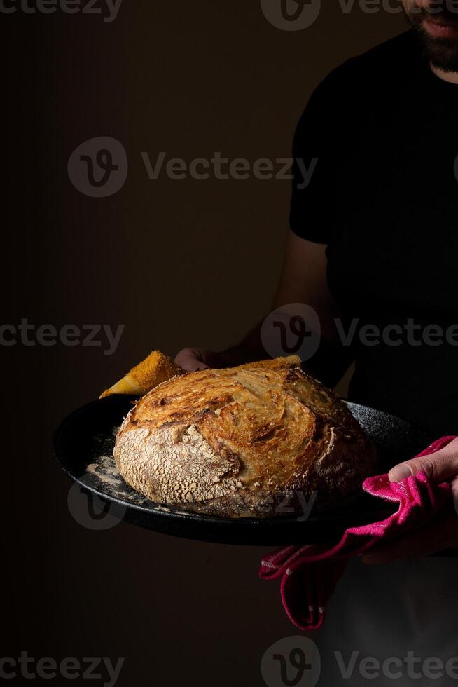 attrayant Jeune caucasien chef posant avec blanc levain pain. photo