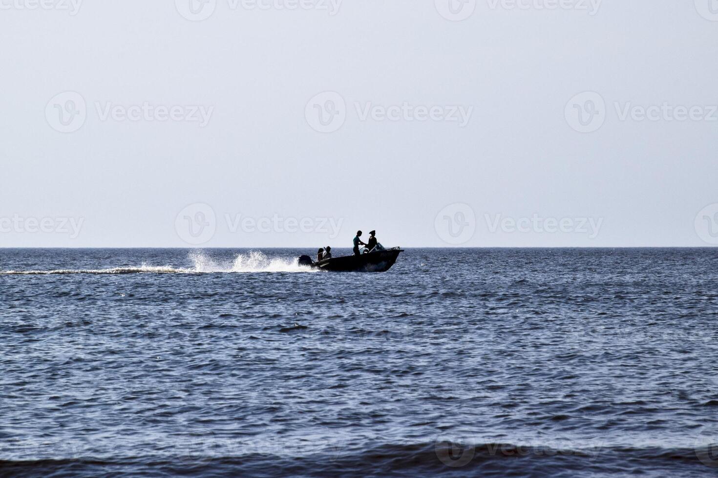 le bateau se précipite par le mer. dans le bateau personnes. paysage marin dans le soir. silhouette de une moteur bateau et gens dans il contre le Contexte de le mer distance photo