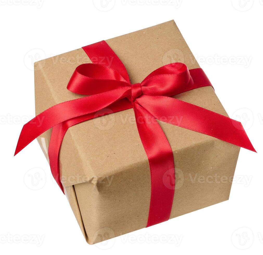 boîte est enveloppé dans marron papier et rouge ruban sur une blanc isolé Contexte photo