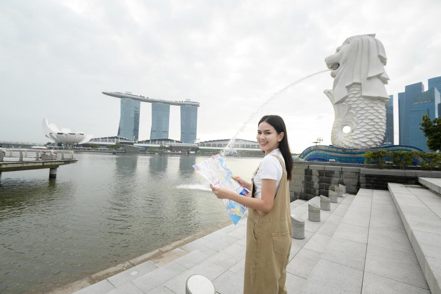 une femme dans merlion Fontaine dans de face de le Marina baie photo