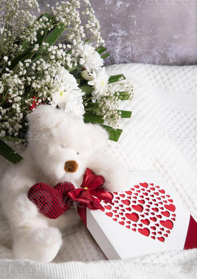 la Saint-Valentin journée cadeau, nounours ours avec une cœur, une boîte de pralines et une bouquet photo