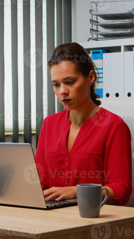 femme d'affaires travail à portable et ordinateur dans même temps. entrepreneur séance dans moderne professionnel bureau, lieu de travail dans personnel entreprise entreprise dactylographie sur ordinateur clavier à la recherche à bureau photo