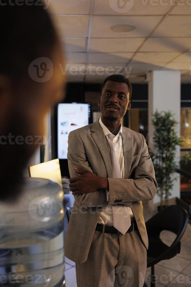 portrait de africain américain homme d'affaire discuter entreprise profit avec collaborateur pendant travail Pause dans Commencez bureau. des employés travail en retard à nuit, Planification investissement stratégie. affaires concept photo