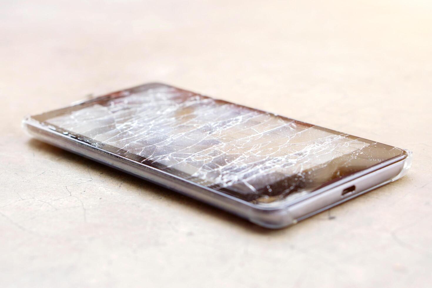 fermer noir mobile téléphone accident tomber à le sol et verre cassé sur vieux et fissuré sol avec Soleil éclater Contexte. photo